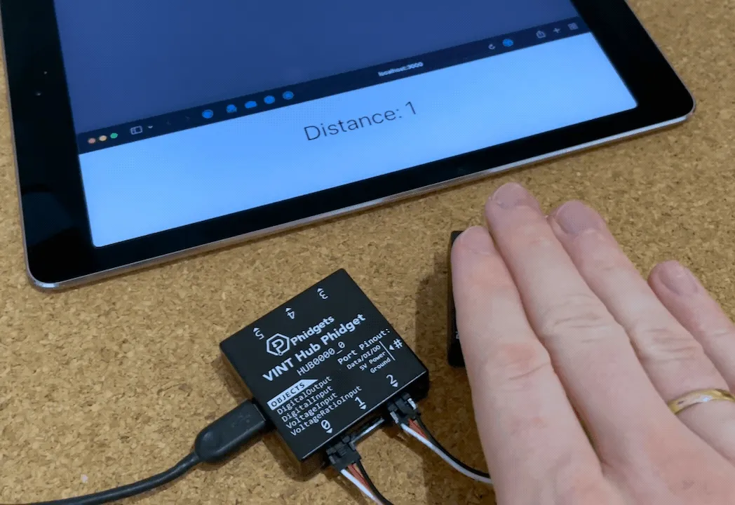 Hand moving closer and further away from the distance sensor showing the distance on a web page